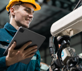 Technician using a tablet beside an industrial robotic arm