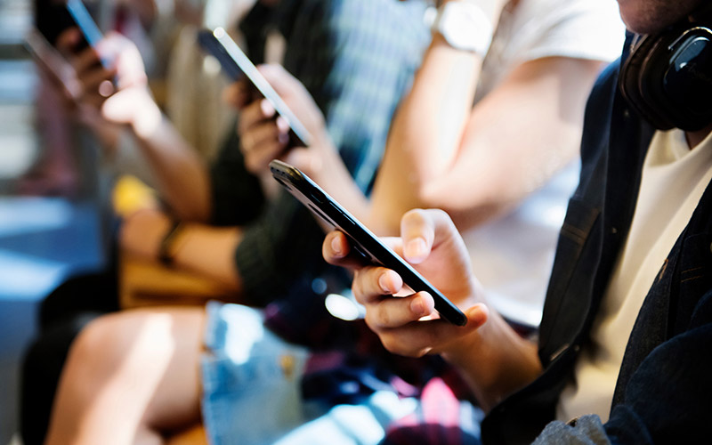 Image showing several people sitting and looking at their smartphones.